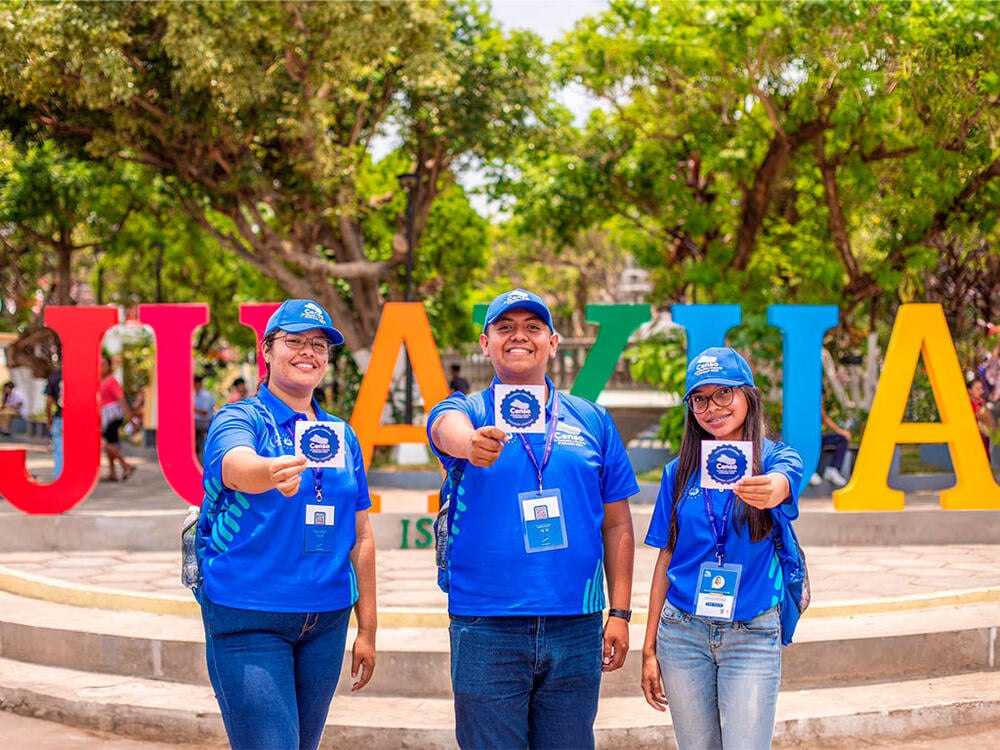 Jóvenes censistas de El Salvador muestran el distintivo que se coloca en todas las casas que son censadas 