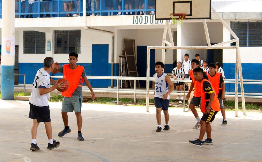 Docentes y estudiantes juegan baloncesto en el torneo organizado.