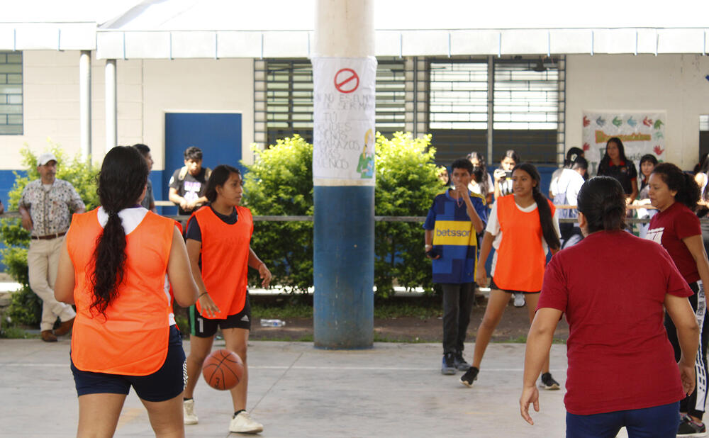 Docentes y estudiantes juegan baloncesto en el torneo organizado.