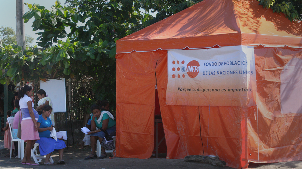 Mujeres se reúnen cerca de una clínica móvil instalada durante una emergencia en El Salvador.