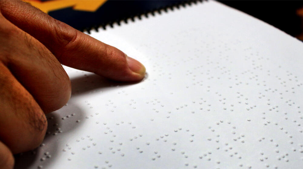 Persona con discapacidad utiliza material de lectoescritura en sistema Braille..